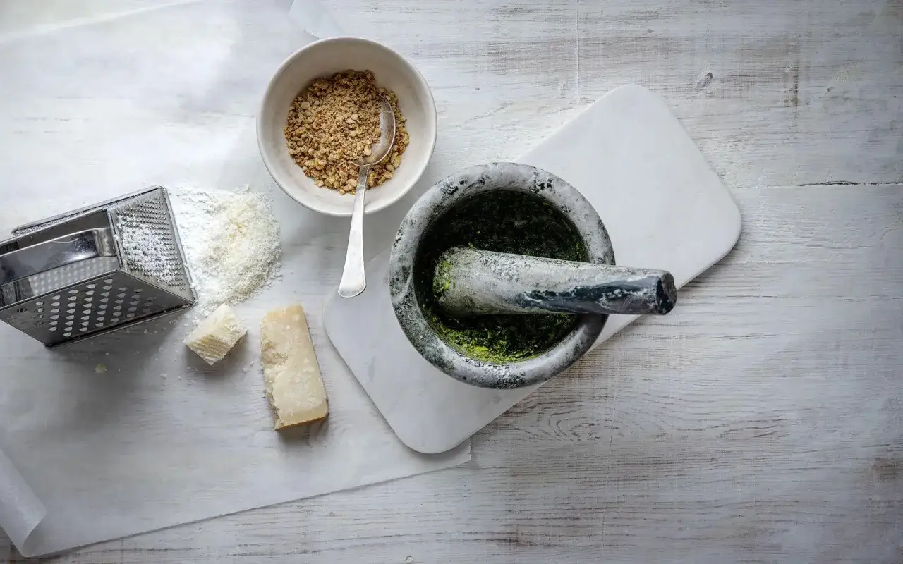 Mortel med basilika, nötter, riven parmesan och ostbitar. Allt för ett gott pesto recept.
