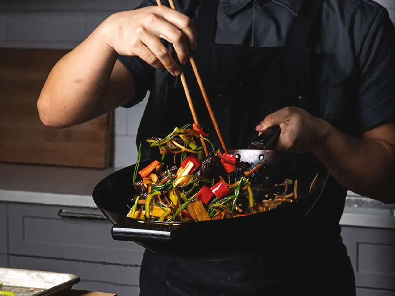 En kock blandar grönsaker och kött i en wok. Ett perfekt wok recept för en snabb och smakrik middag.