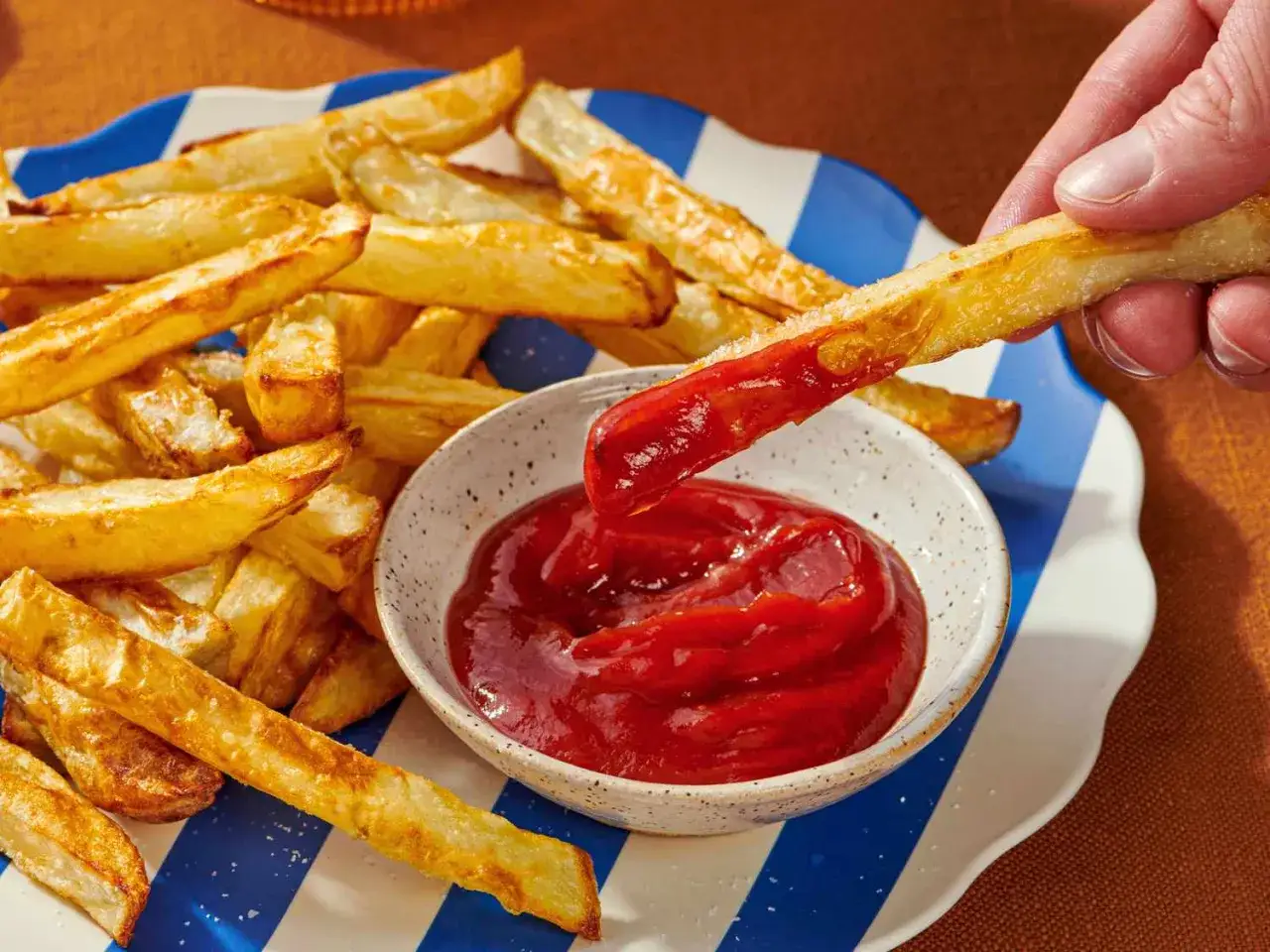 Krispiga pommes frites, perfekt tillagade i airfryer, doppas i ketchup.