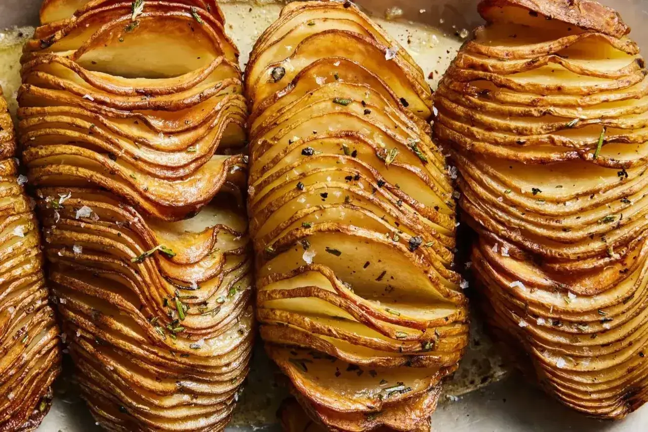 Krispiga hasselbackspotatisar med örter och flingsalt, redo att serveras. Ett perfekt hasselbackspotatis recept för alla tillfällen.
