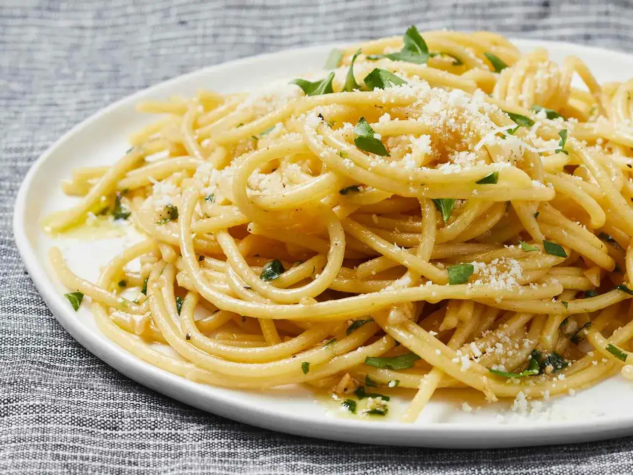 En tallrik spaghetti aglio e olio, ett enkelt men smakrikt pasta recept. Garnerad med riven parmesan och färsk persilja.