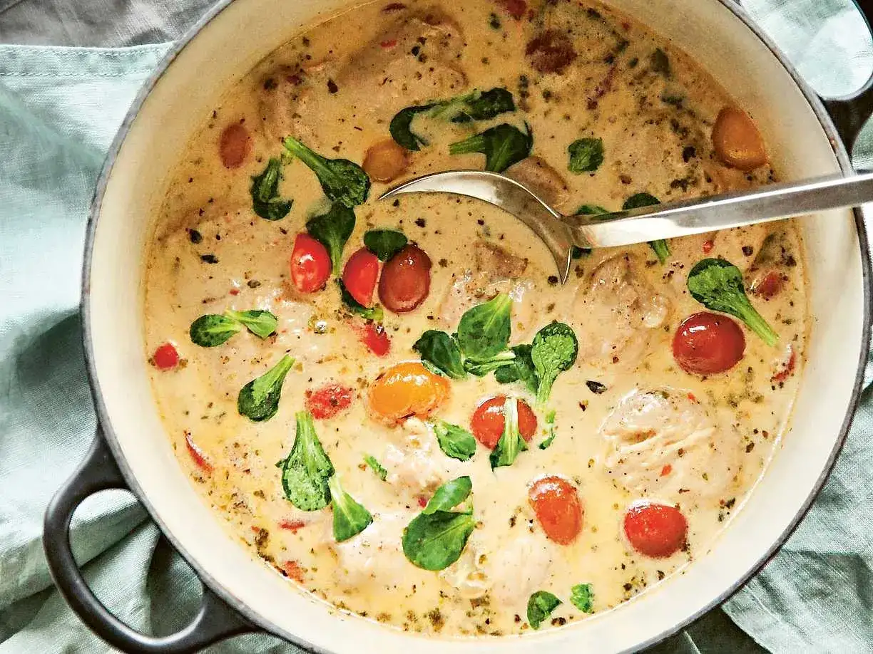 En krämig kycklinggryta med körsbärstomater och gröna blad. Ett enkelt kyckling recept som ser utsökt ut.