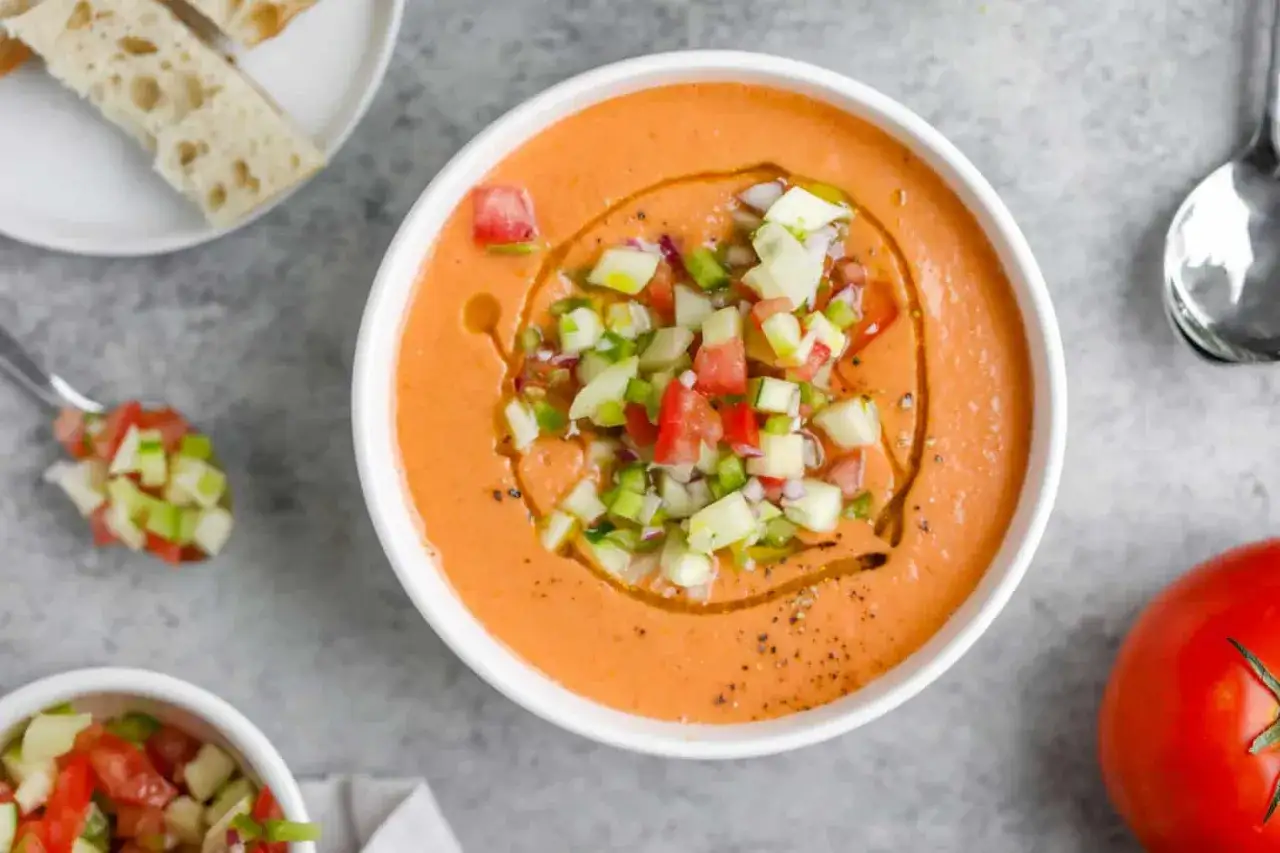 En skål med krämig gazpacho, toppad med tärnade grönsaker och olivolja. Perfekt för ett uppfriskande gazpacho recept.