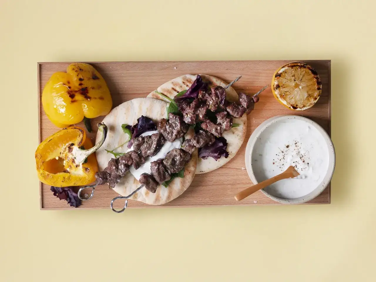 Grillad köttspett med pitabröd, grillad paprika, citron och tzatziki. Ett perfekt souvlaki recept för sommaren.