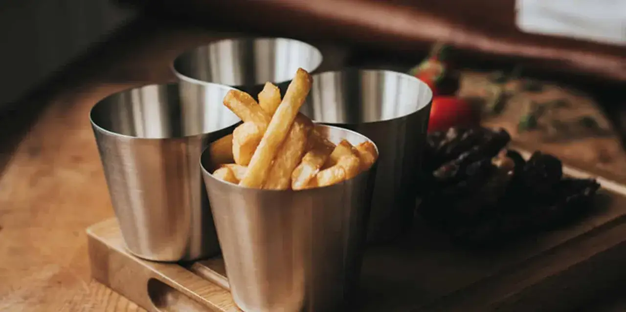 Friterade pommes i kastrull, redo att serveras.