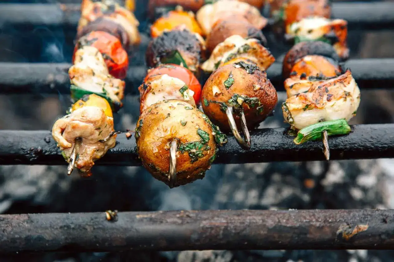 Grillspett med kyckling, champinjoner och grönsaker som ryker på grillen. Ett perfekt grillspett recept för sommaren.