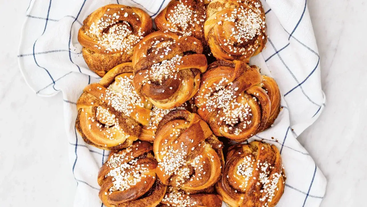 En hög med gyllene kanelbullar, toppade med pärlsocker, som om Camilla Hamid precis bakat dem.