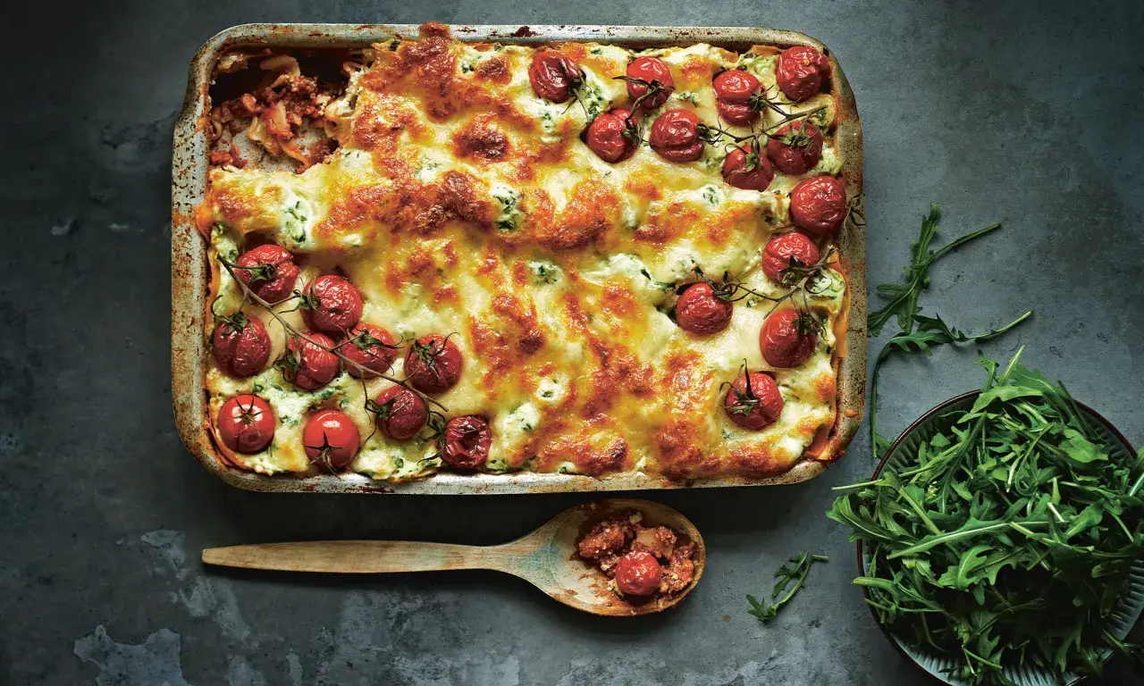 En gyllene lasagne toppad med k&ouml;rsb&auml;rstomater och ost. Perfekt vin till lasagne.