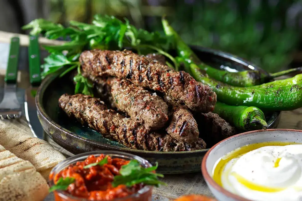 Grillade cevapcici med gröna paprikor, persilja, bröd och en röra. Ett perfekt cevapcici recept för sommaren.