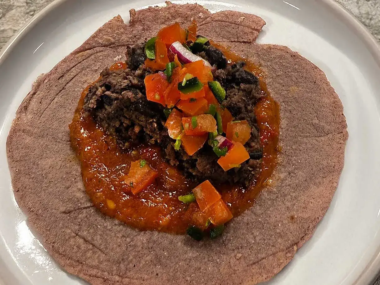 En lila tortilla med refried beans, salsa och hackade grönsaker. Ett enkelt refried beans recept att prova.