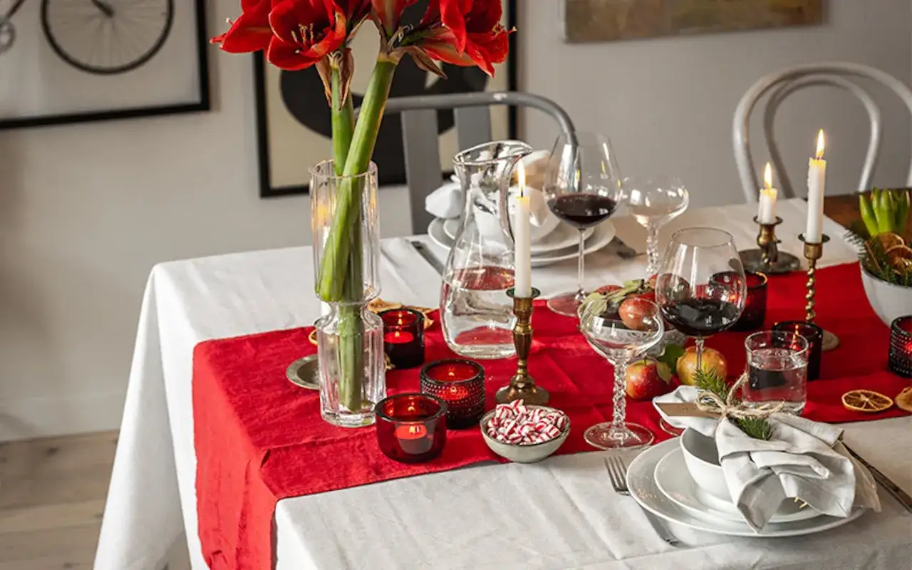 Vackert dukat julbord med röda amaryllisar, levande ljus och glas med vin till julbordet.