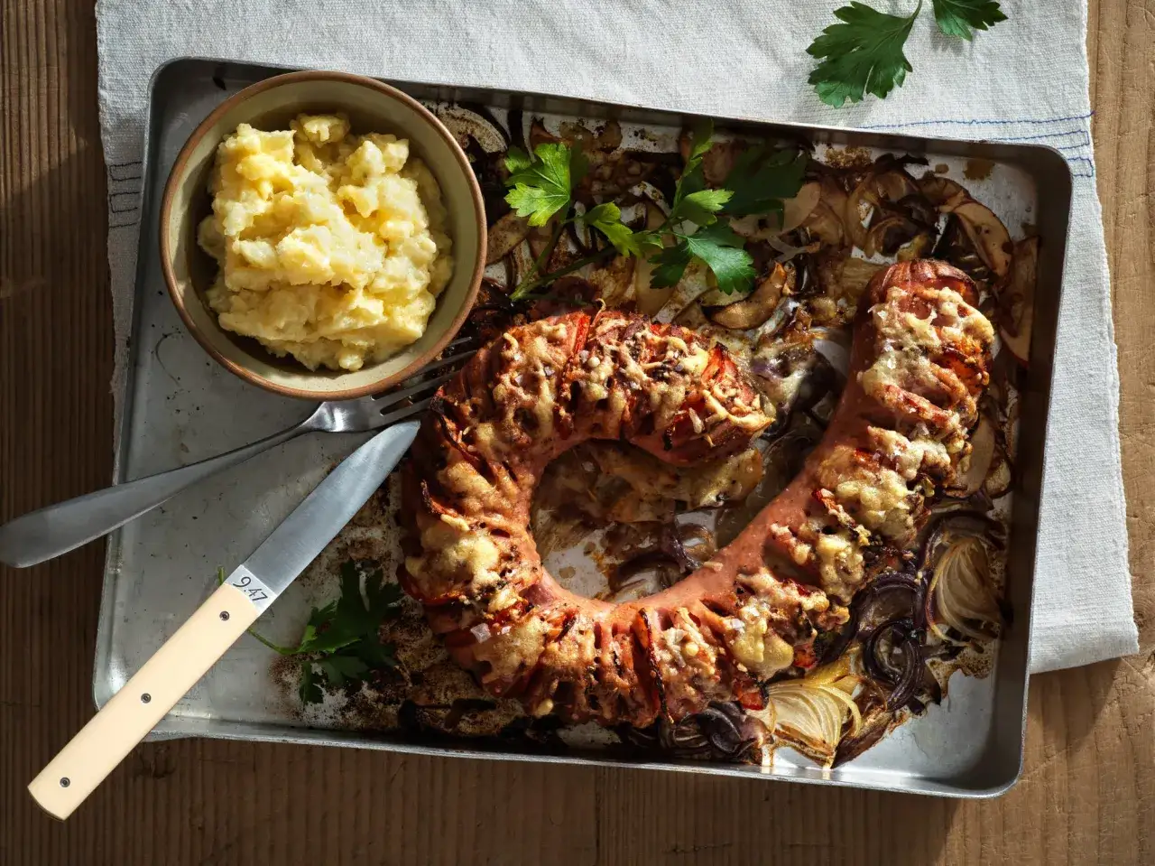 En ring av falukorv med ost och tomat, bakad med lök. Serveras med potatismos. Ett enkelt falukorv recept.