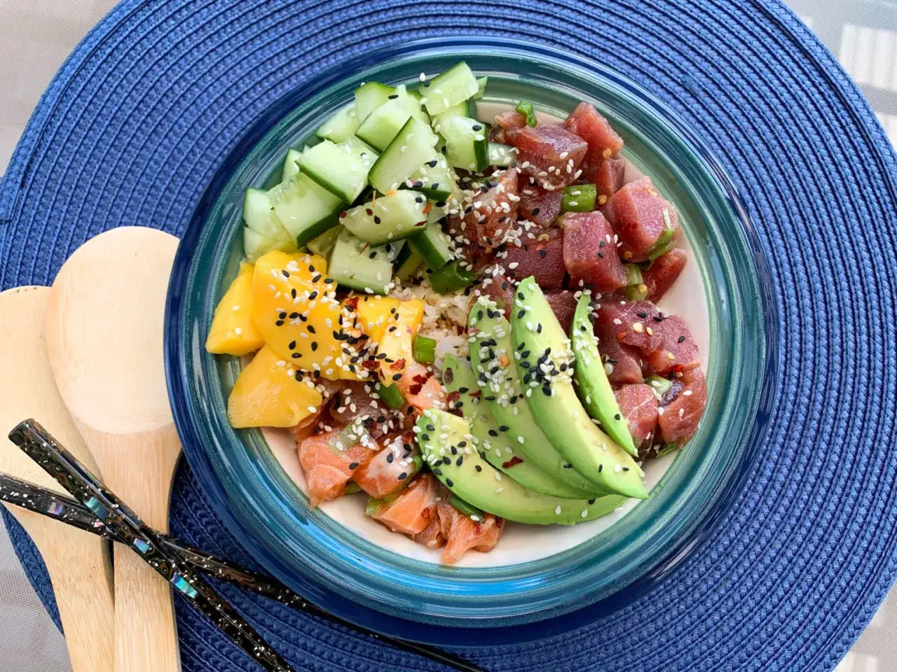 En färgglad poke bowl med tonfisk, lax, mango, avokado och gurka, toppad med sesamfrön.