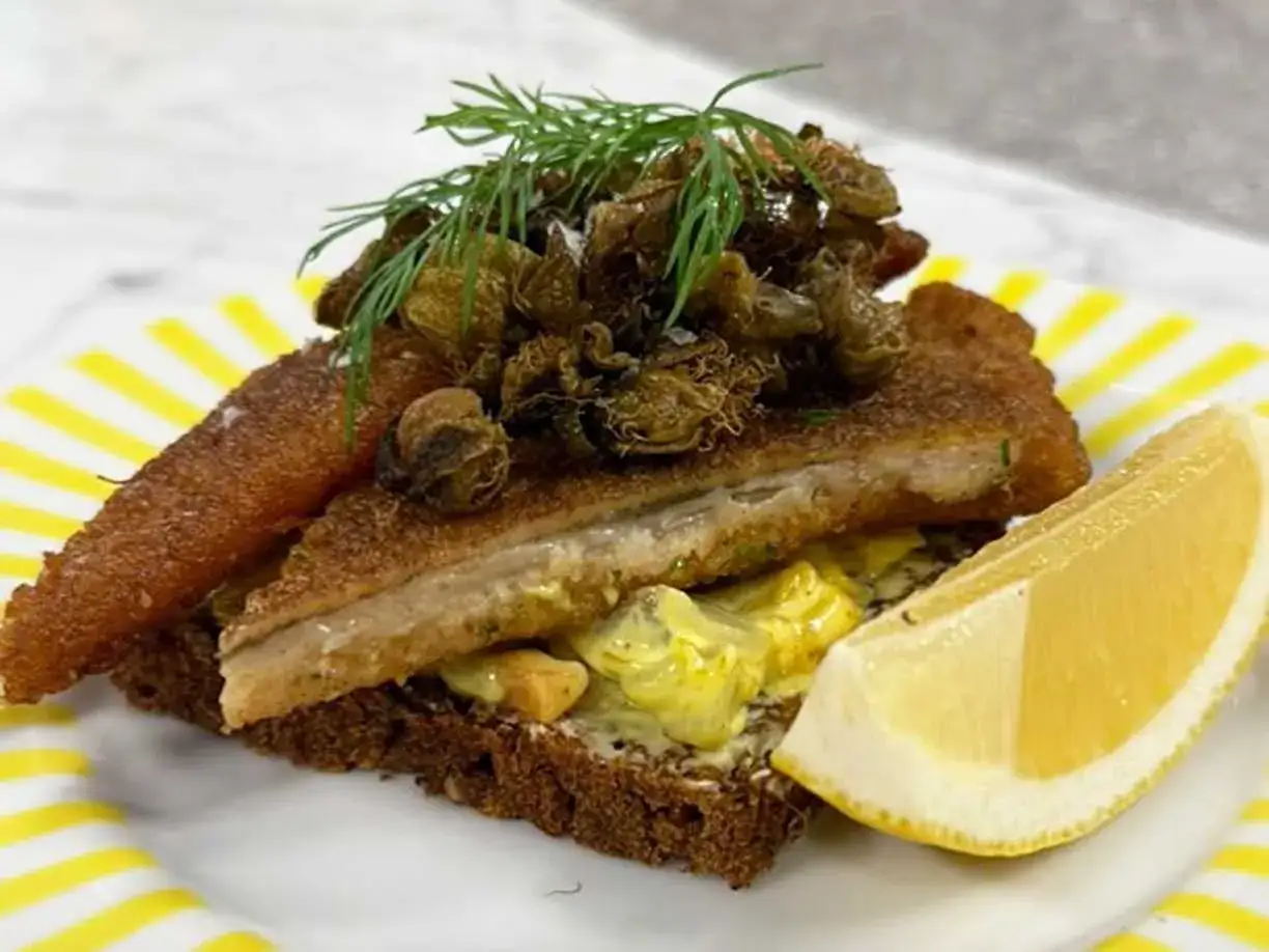 Sm&ouml;rg&aring;s med stekt fisk, toppad med kapris och dill, serverad med en klick dansk remoulads&aring;s och en citronskiva.