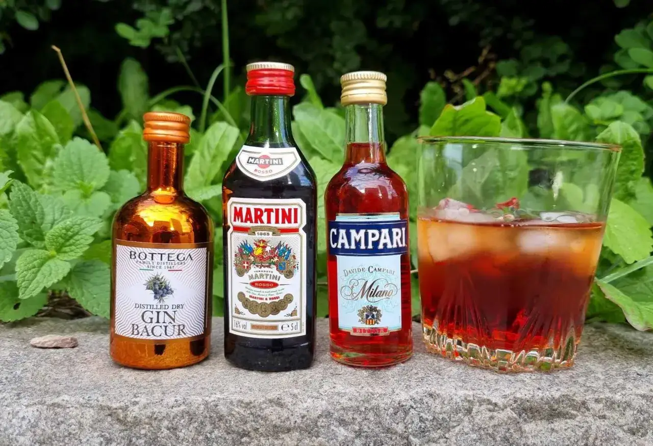 Mini-flaskor med gin, Martini Rosso och Campari, redo för ett negroni recept. En färdigblandad negroni i glas.