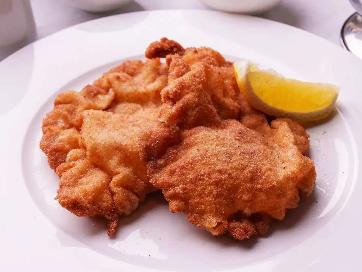 Två gyllene schnitzlar med citronklyfta, perfekt för ett klassiskt schnitzel recept.
