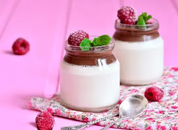 Två glas med choklad- och vaniljpannacotta, toppade med hallon och mynta. Perfekt som dessertvin till pannacotta.