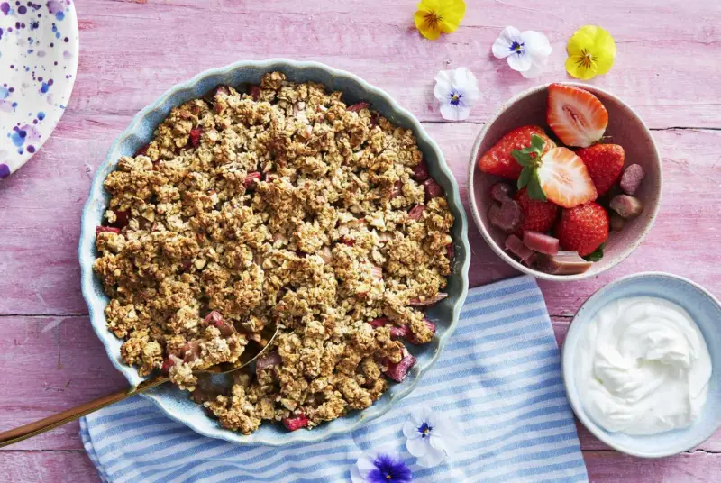En härlig gammaldags rabarberpaj med krispigt täcke, serverad med färska jordgubbar och grädde. Perfekt sommardessert!